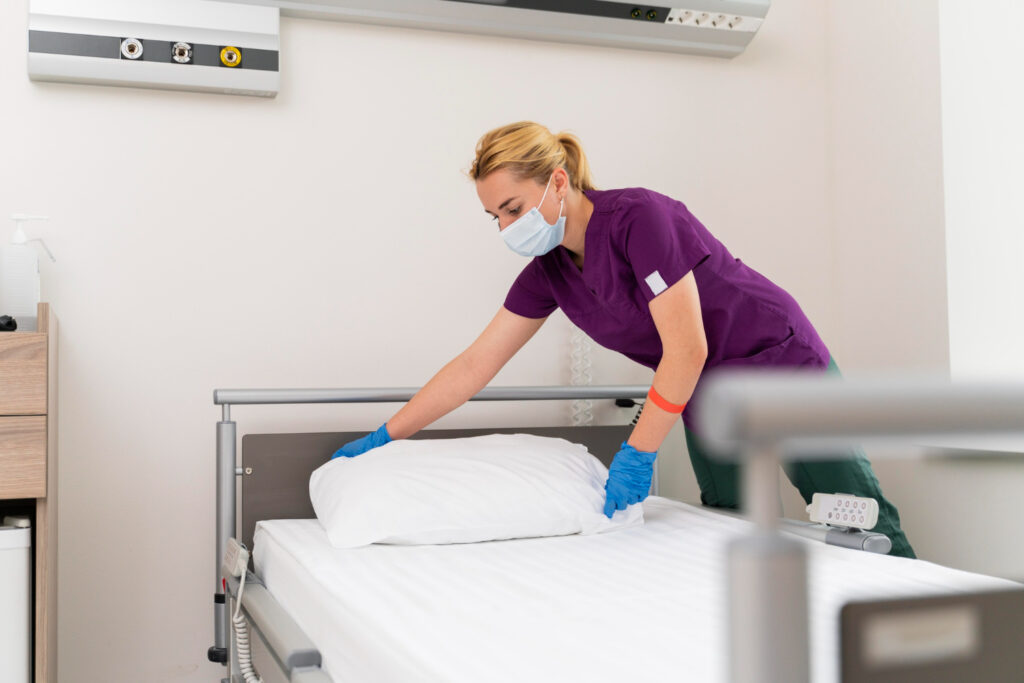 healthcare worker making a patient's bed